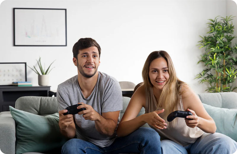 Two people sitting on a couch playing video games with controllers.